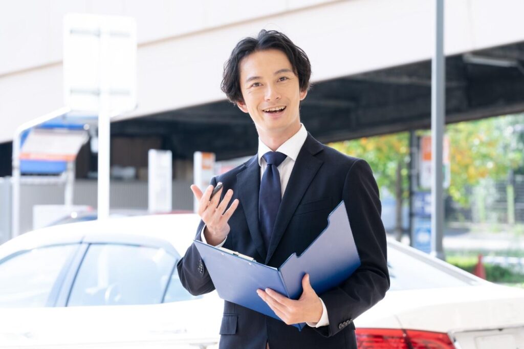 車の前に立つ営業マン