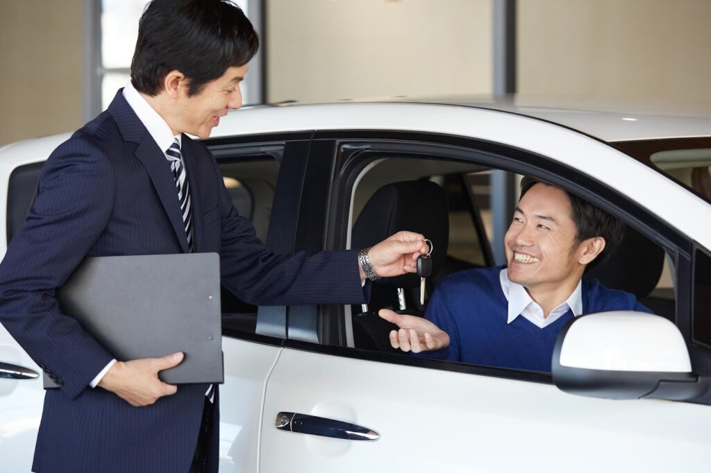 営業スタッフと車内でキーを受け取っている男性