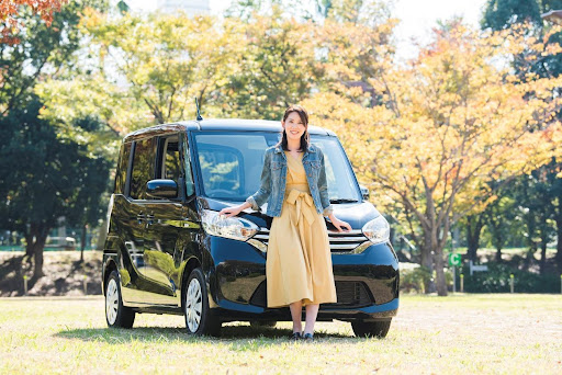 黒い軽自動車のフロントに寄りかかる女性