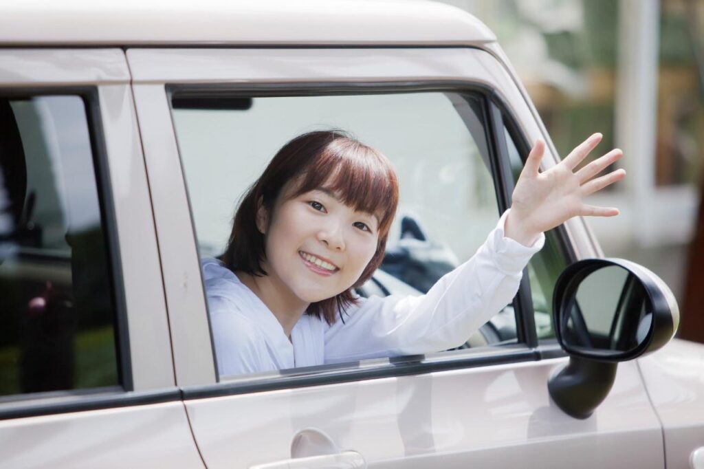 車の窓から手を振る女性