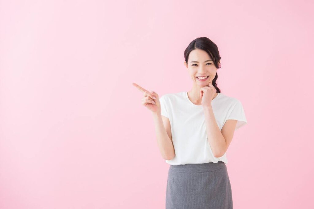 右手で右方向に指さしをしている女性