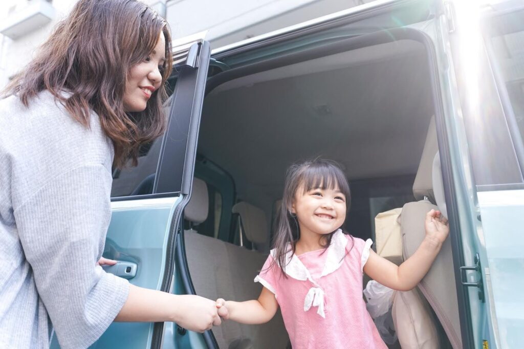 車から降りてくる少女とサポートしている女性