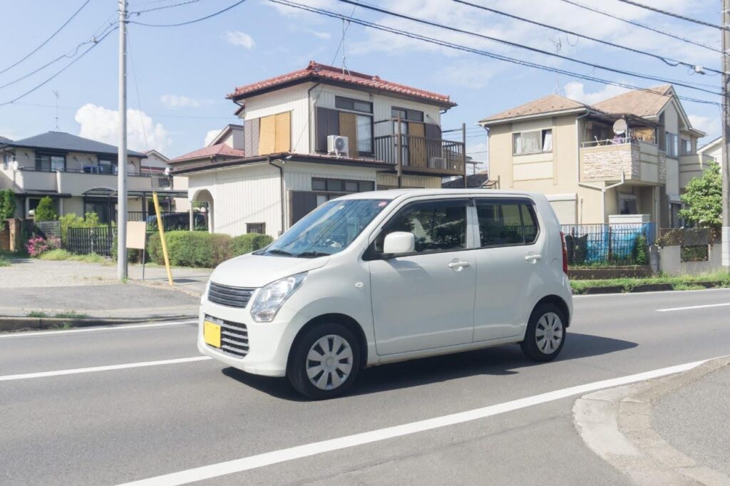 住宅街を走行する白い1台の軽自動車