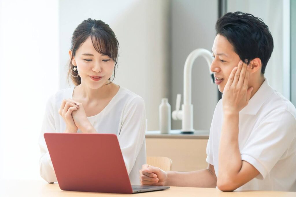 パソコンの画面を見つめる夫婦