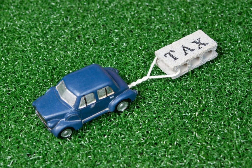 「TAX」と書かれたブロックを引きずるミニカー