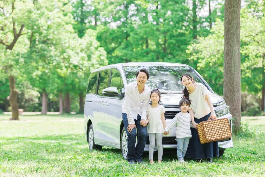 公園の中に停車したミニバンの前で並ぶ家族