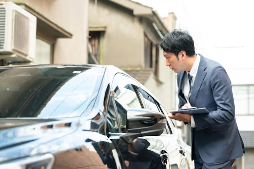 住宅街で車の査定をするビジネスマン