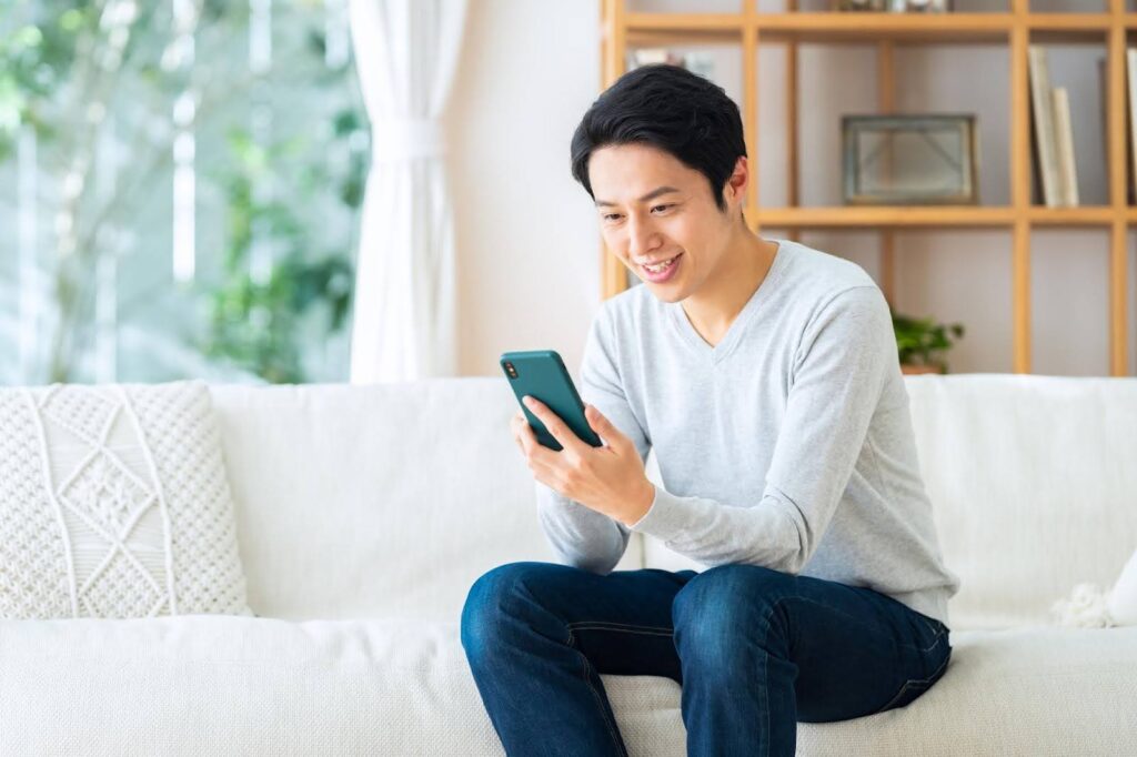 リビングでスマートフォンを操作する男性