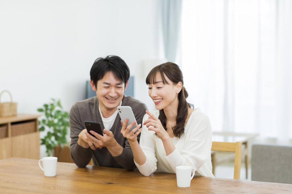 スマートフォンで調べものをする笑顔の夫婦