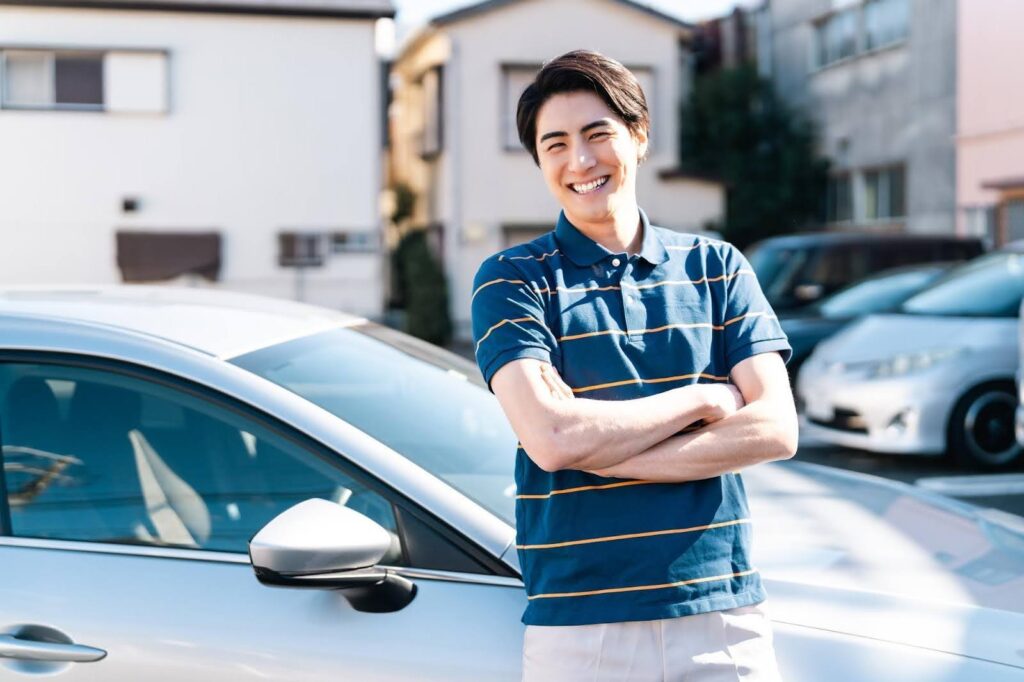 車の横に立つ笑顔の若い男性
