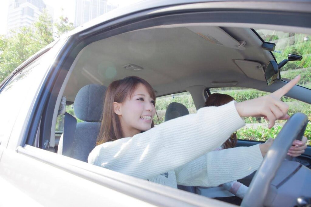 運転席で前方に指を向ける女性