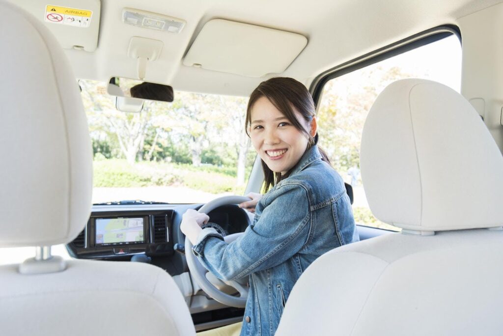 車の運転席に座る笑顔の若い女性