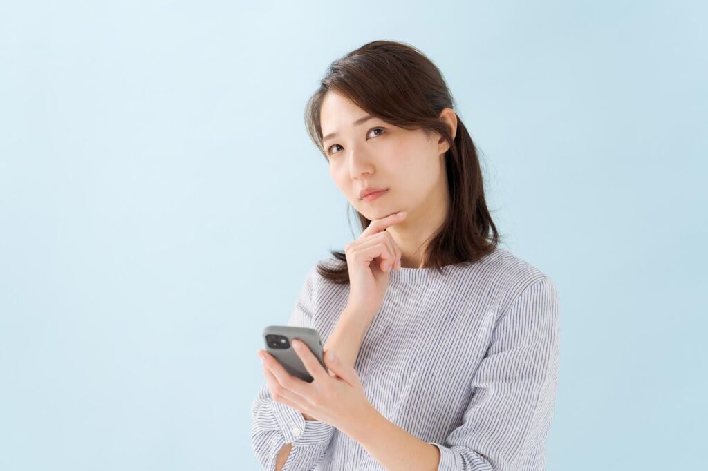 スマートフォンを持って考え事をする若い女性