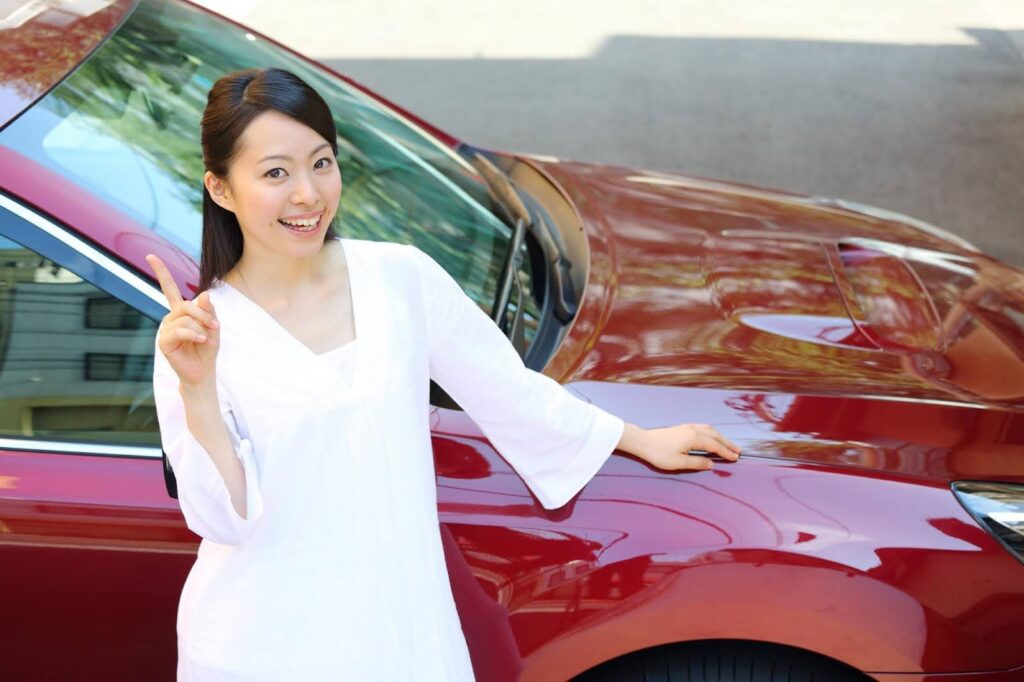 車の横に立つ笑顔の若い女性