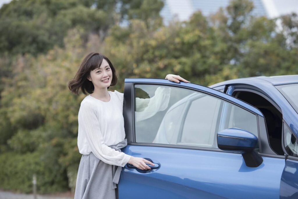 車のドアを開ける笑顔の若い女性