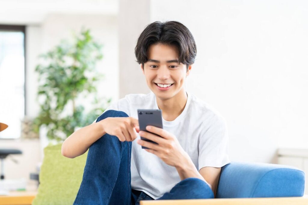 スマートフォンを操作する笑顔の若い男性