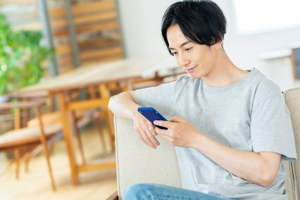 スマートフォンの画面を眺める若い男性