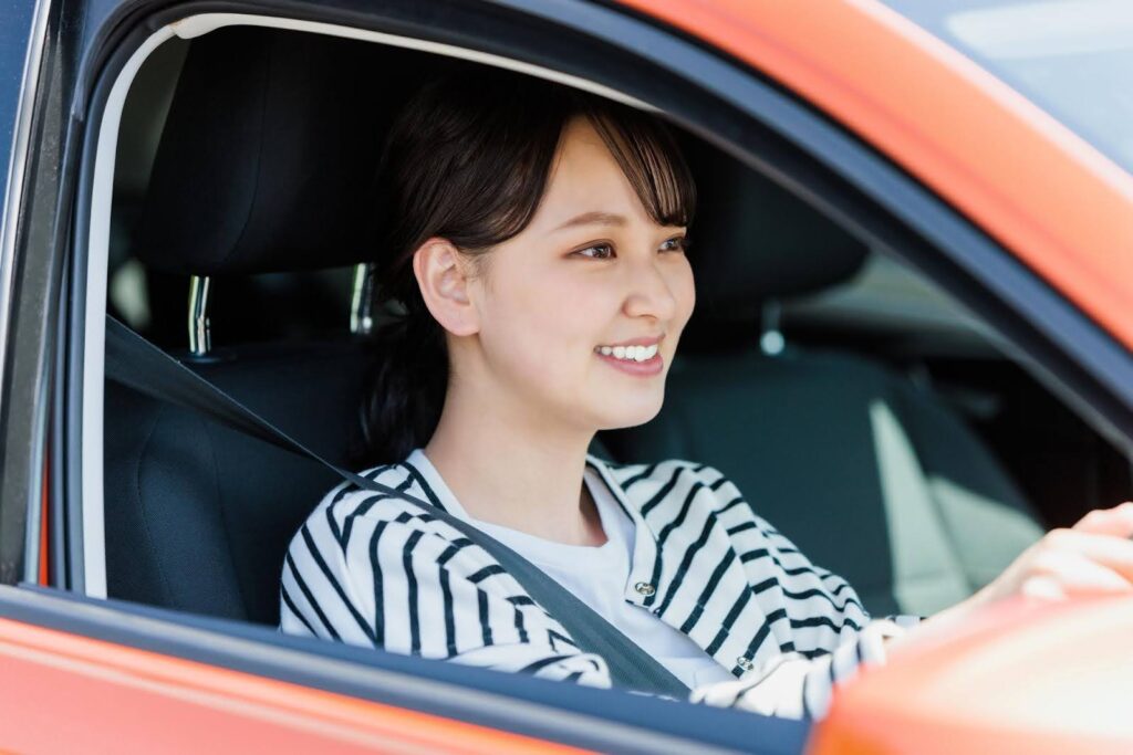 車を運転する笑顔の若い女性