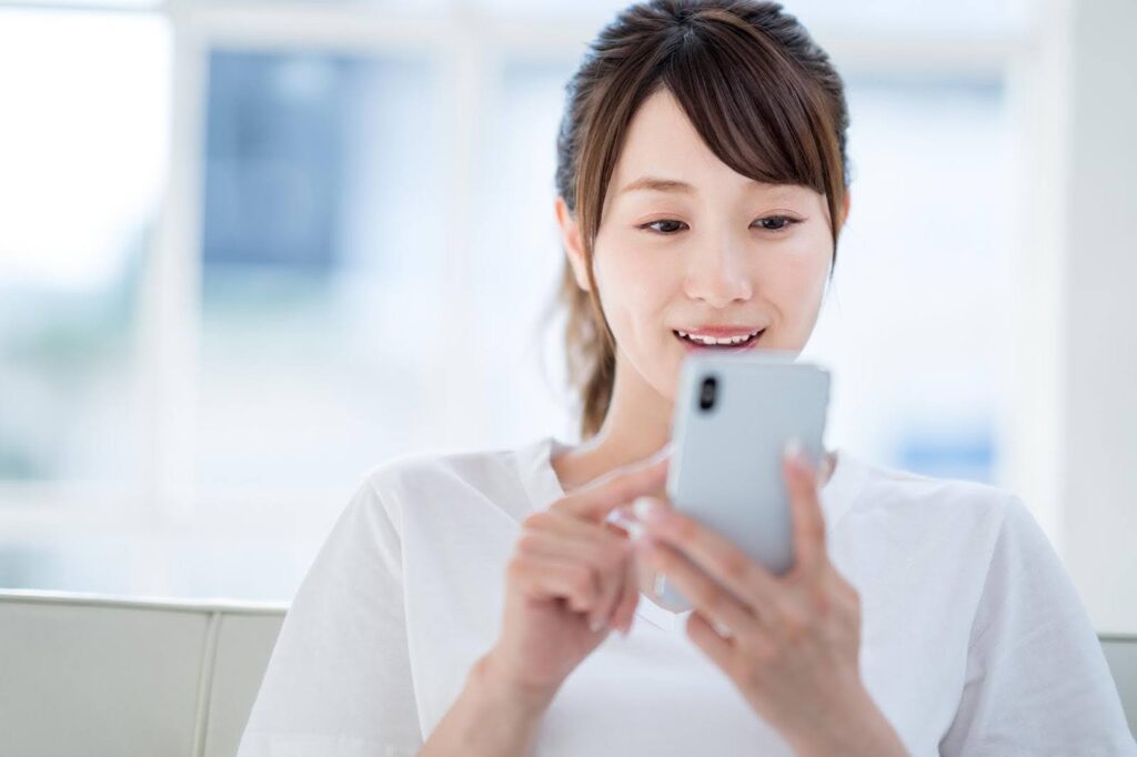 スマートフォンの画面を見て喜ぶ若い女性