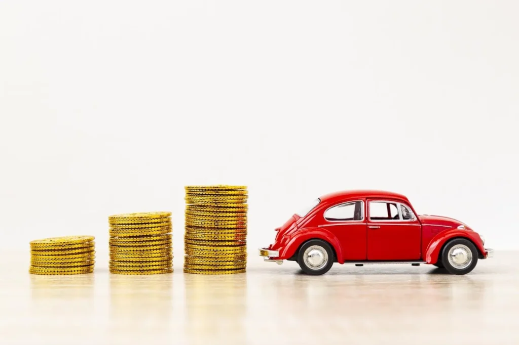 右肩上がりに積まれたコインとミニカー