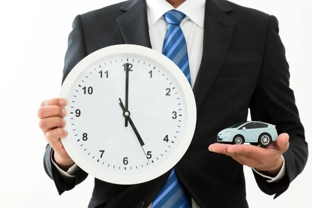 時計とミニカーを持つスーツ姿の人