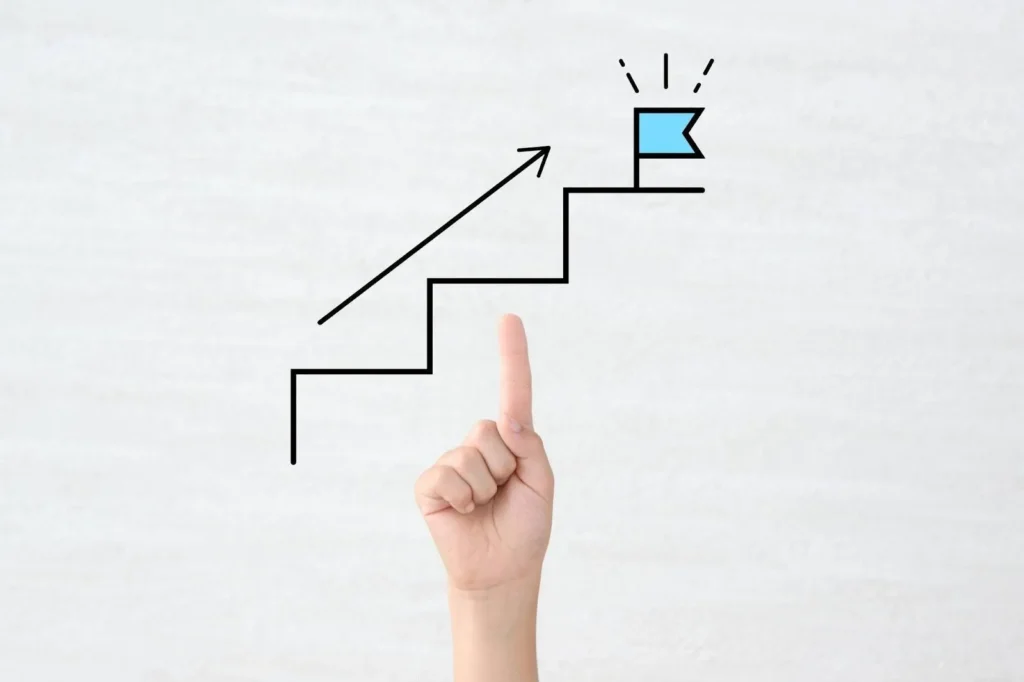 階段の上にゴールの旗が立つデザインを指さす様子