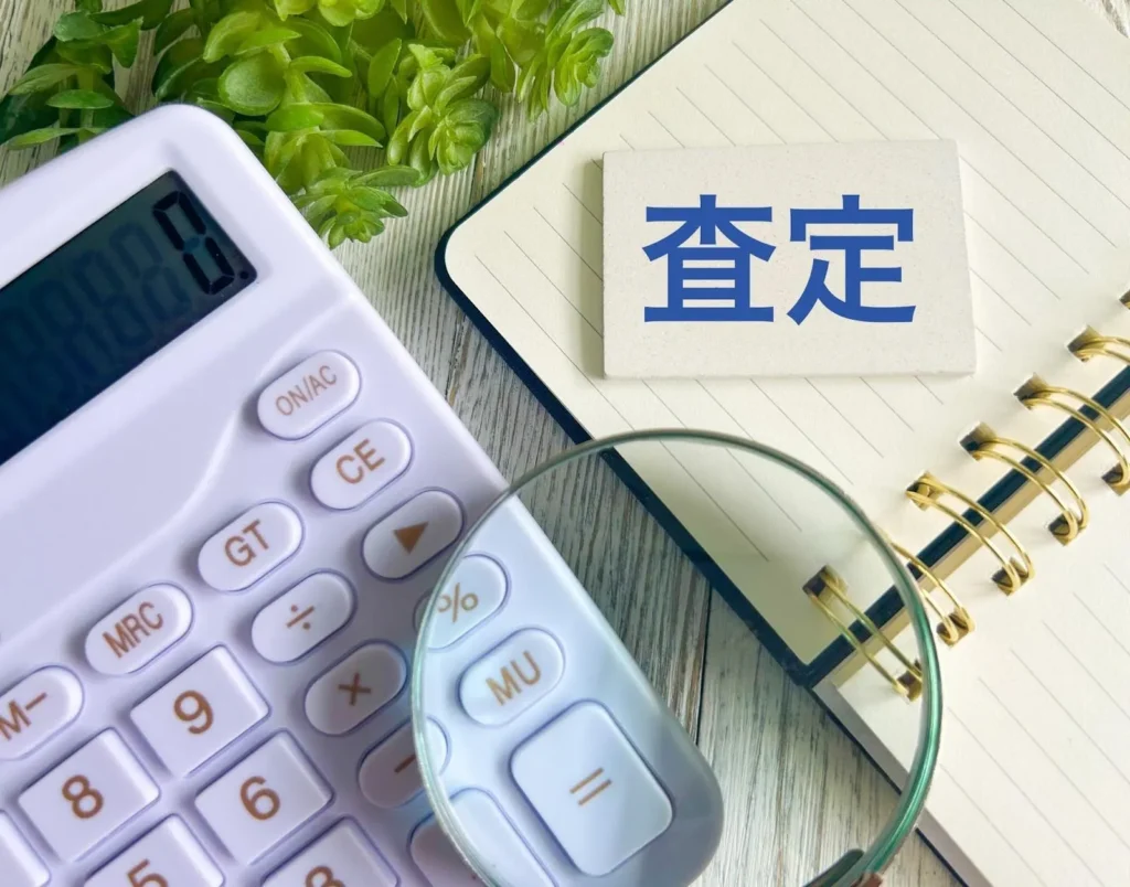 電卓や虫眼鏡と査定と書かれたプレート