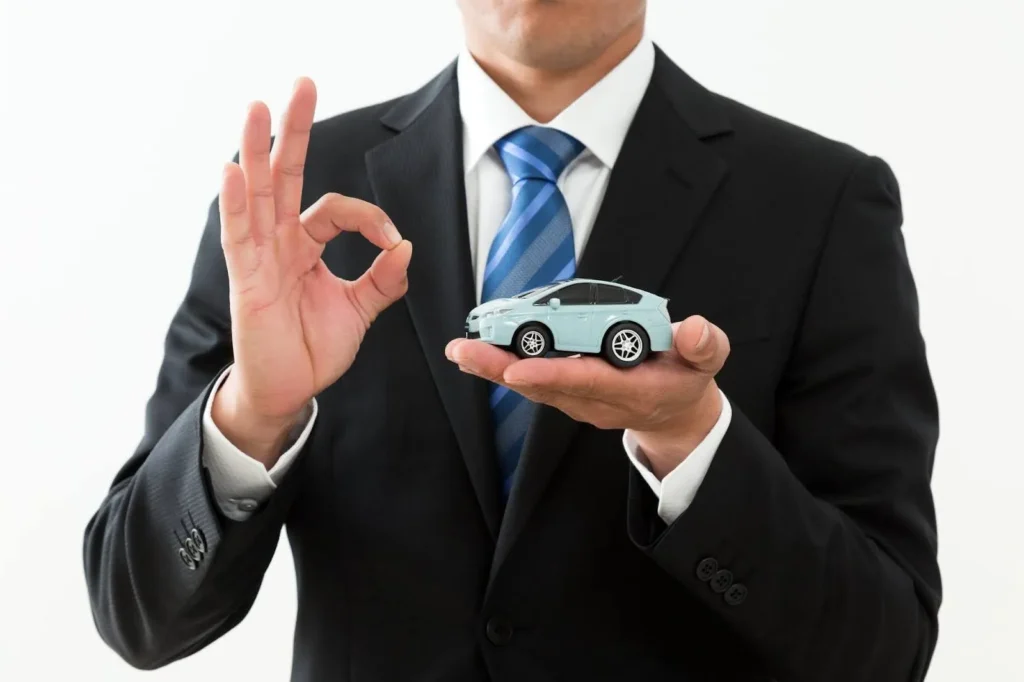 ミニカーを持ってOKサインをする男性