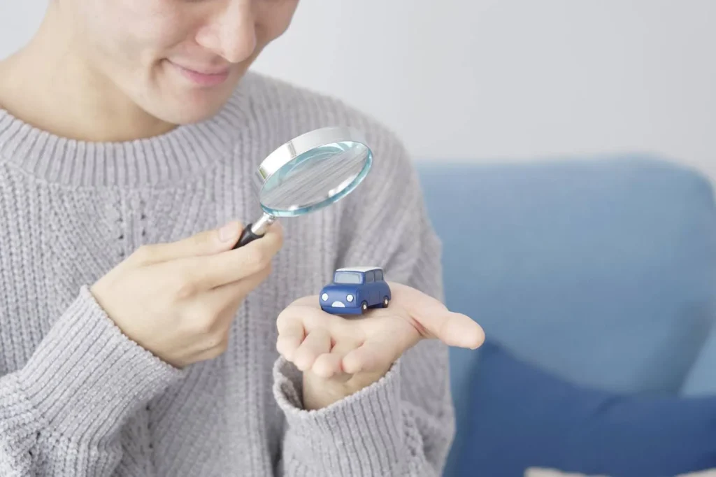 ミニカーを持って虫メガネで覗き込む様子