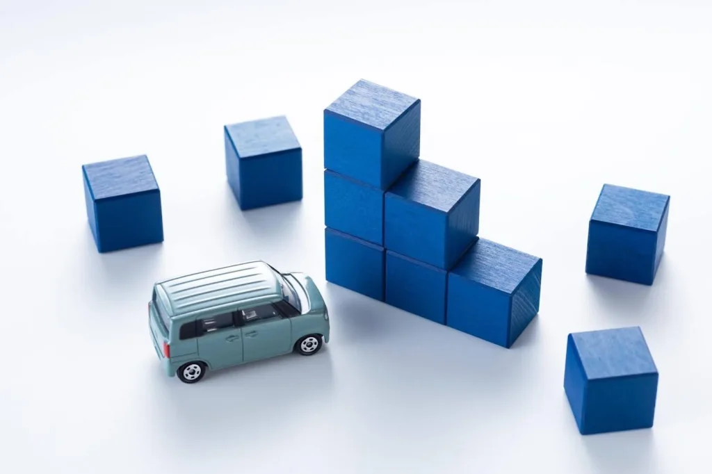 右肩下がりに置かれた青い積み木とミニカー